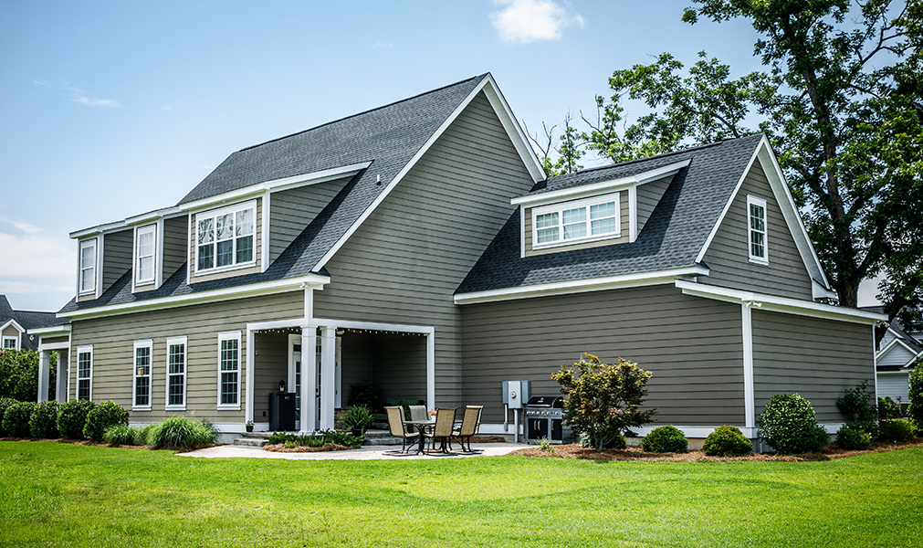 Angled view of the back of a residential single family house that has a gray shingle roof.