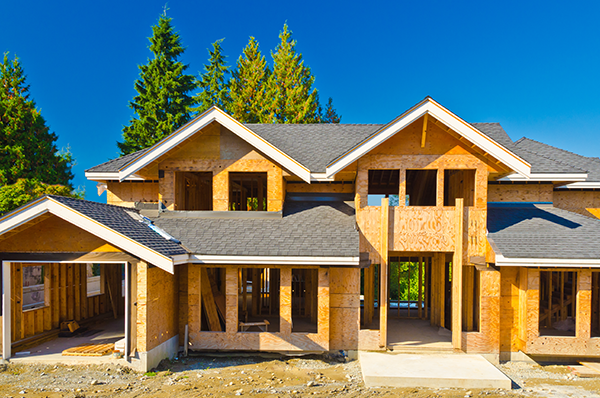 front view of a residential house under construction. Framing and the roof are whats finished on the house.