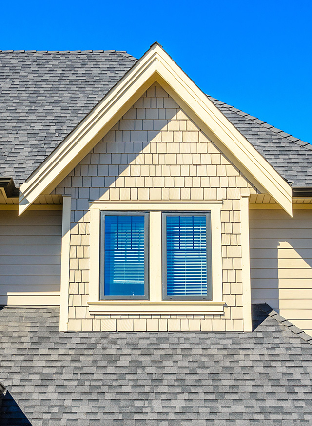 close up of a gray shingle roof above a second story window of a home.