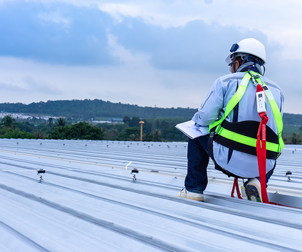 Close up of the back of a commercial roofing contractor on the top of a metal commercial roof.